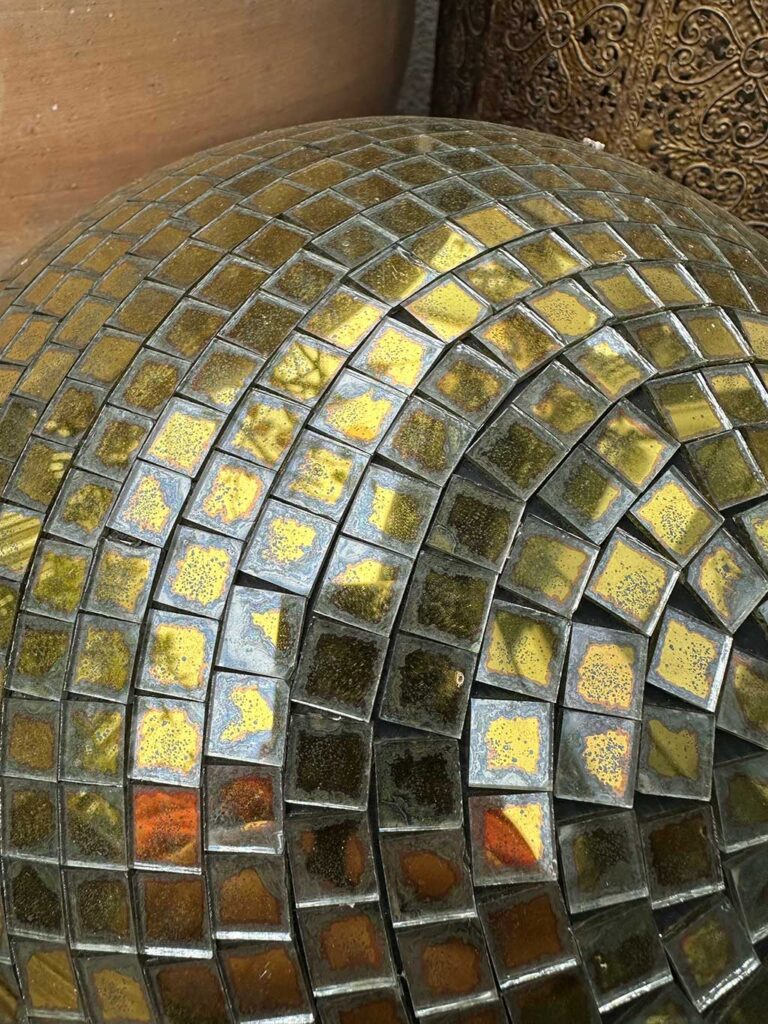 Gold mirror ball after 3 years outdoors showing partial delamination and fading
